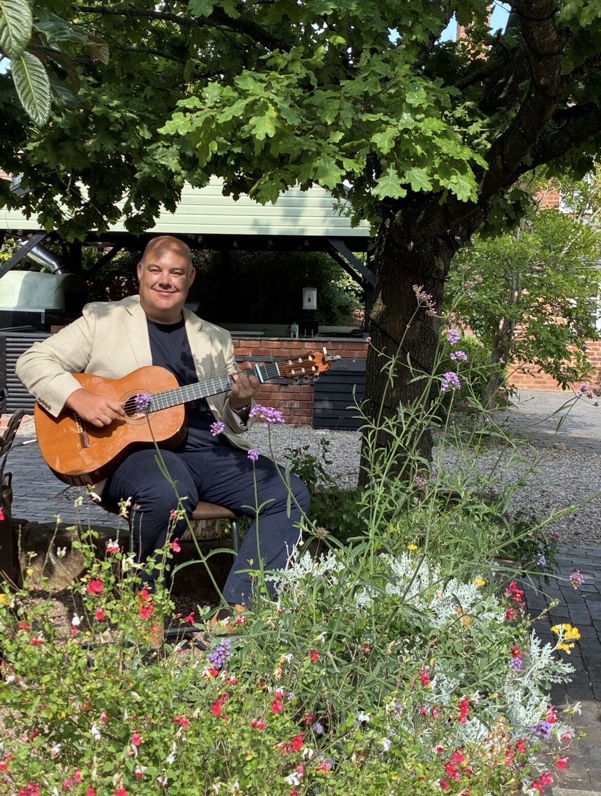 Wedding guitarist Stuart Toogood playing acoustic guitar outdoors in a garden