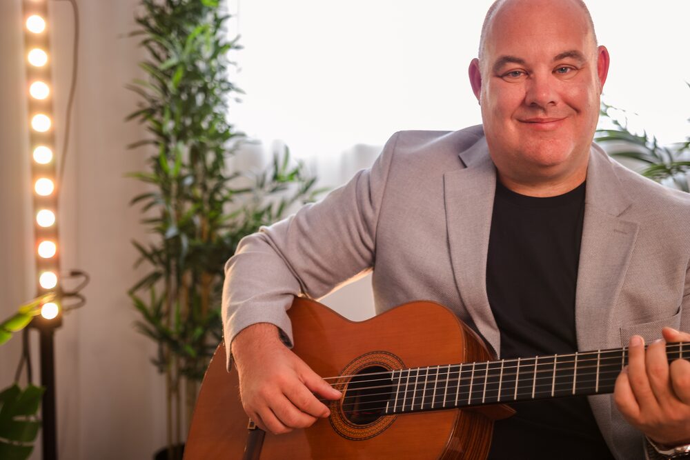 Stuart Toogood, wedding guitarist, playing acoustic guitar in a warm indoor setting